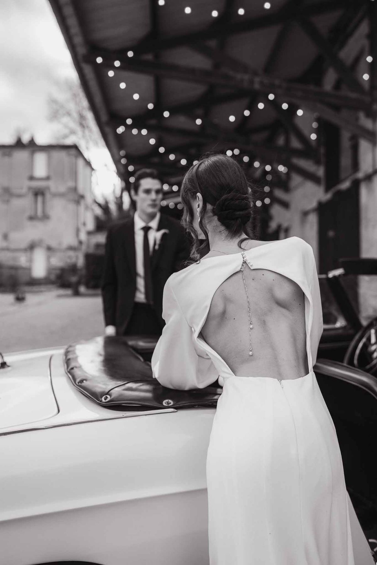Couple by vintage car under festoon lights at Chateau d'Hazeville