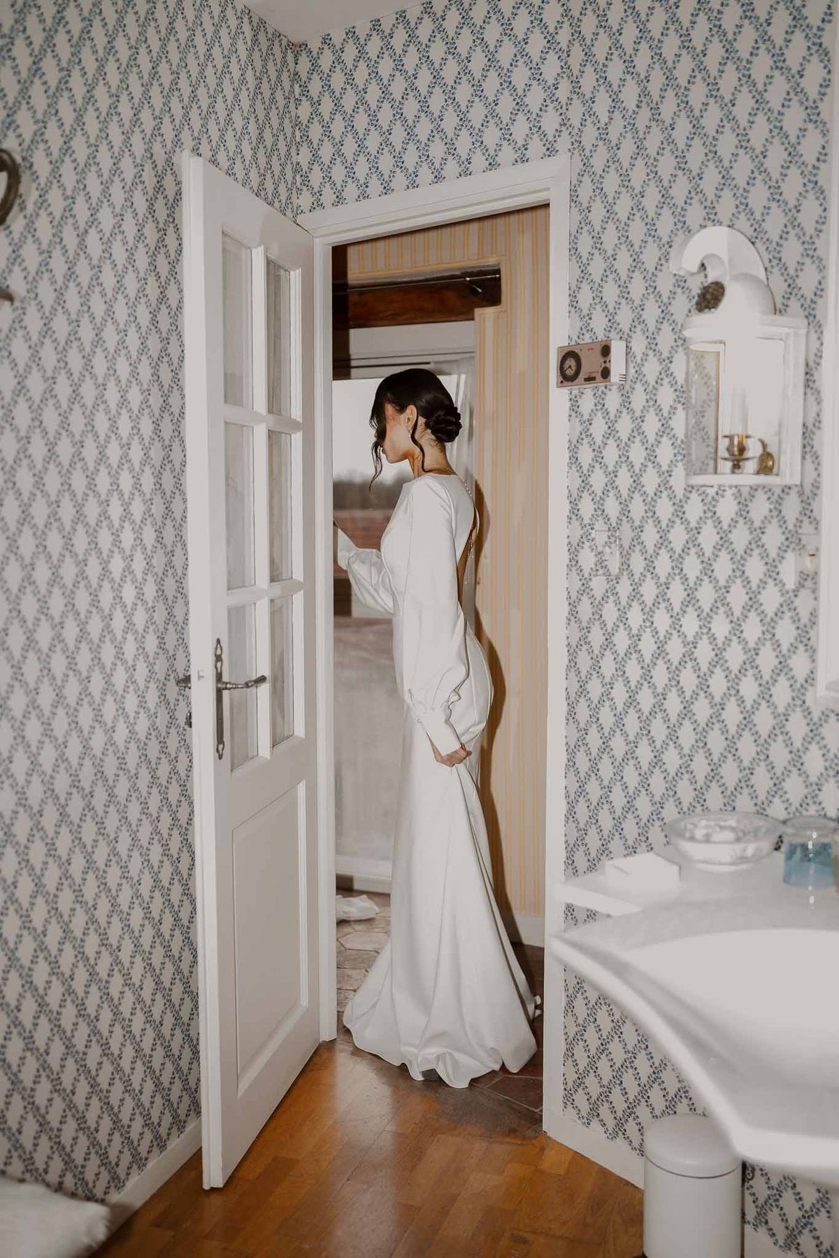 Bride in doorway of wallpapered room at Chateau d'Hazeville