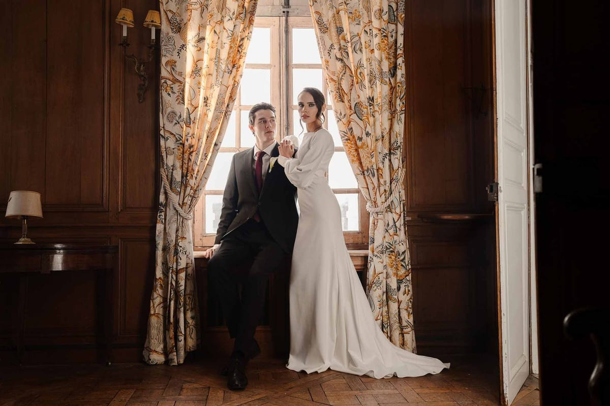 Couple in window seat with toile curtains at Chateau d'Hazeville