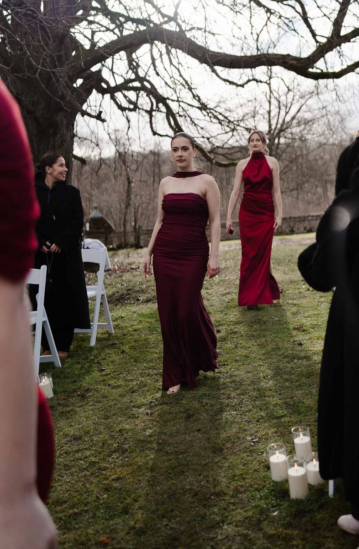 Bridesmaids in burgundy walking on lawn at Chateau d'Hazeville