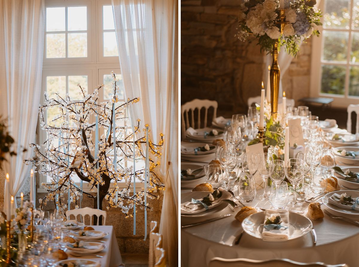 A two-panel detail shot of an indoor wedding reception tablescape set in what appears to be a French château or stone-walled venue. The left panel shows a decorative blossom tree centerpiece with warm fairy lights and pale blue ribbon hangings, positioned in front of sheer ivory curtains and tall windows, flanked by gold taper candles and white Napoleon chairs. The right panel offers a close-up of the table setting, featuring a pale grey linen tablecloth, white china plates with folded linen napkins, multiple crystal wine glasses, tall white taper candles in gold candlesticks, and a high floral arrangement of white roses and pale blue hydrangeas in a gold vase. Small green botanical elements and pale blue accent details are scattered across the place settings alongside individual bread rolls and place cards. The overall decor palette combines ivory, pale blue, gold, and soft green in a classic French-inspired style.