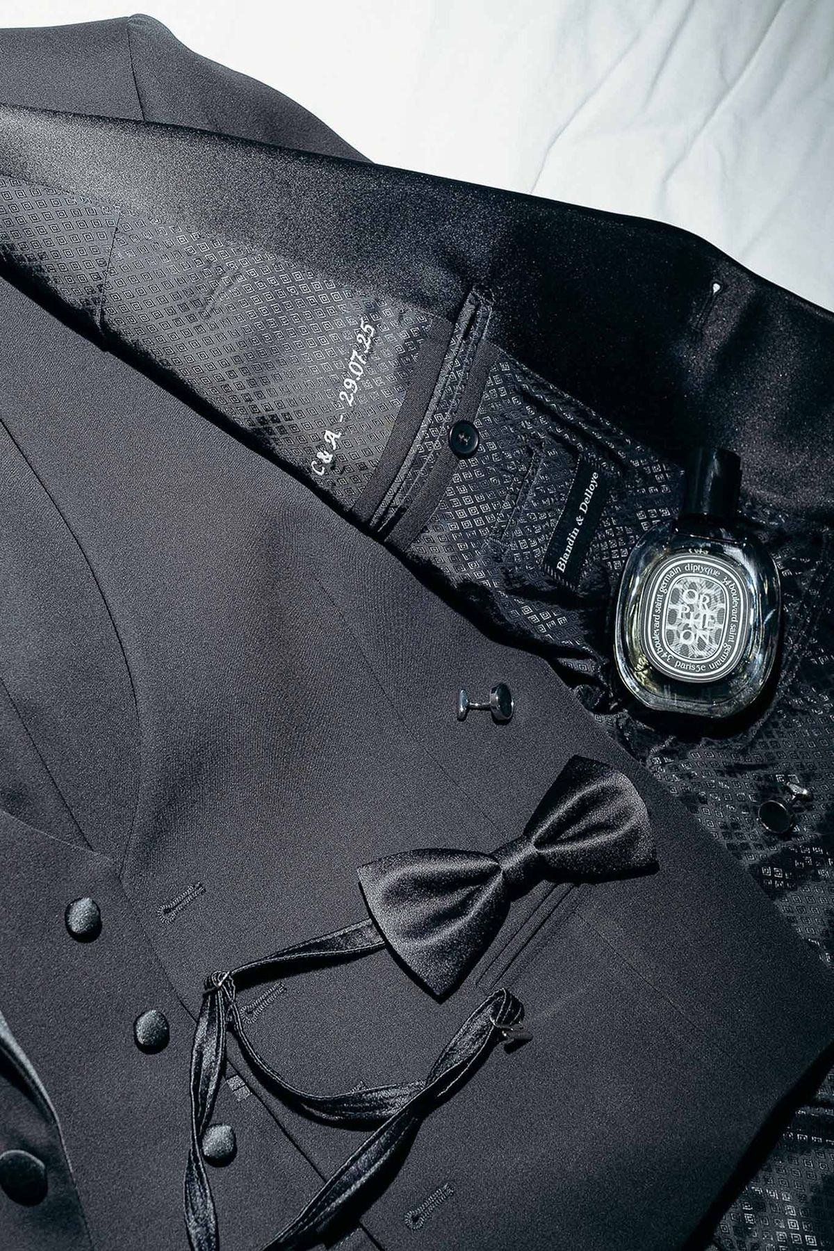 Groom's black suit accessories and perfume flat lay at Domaine de Perrotin