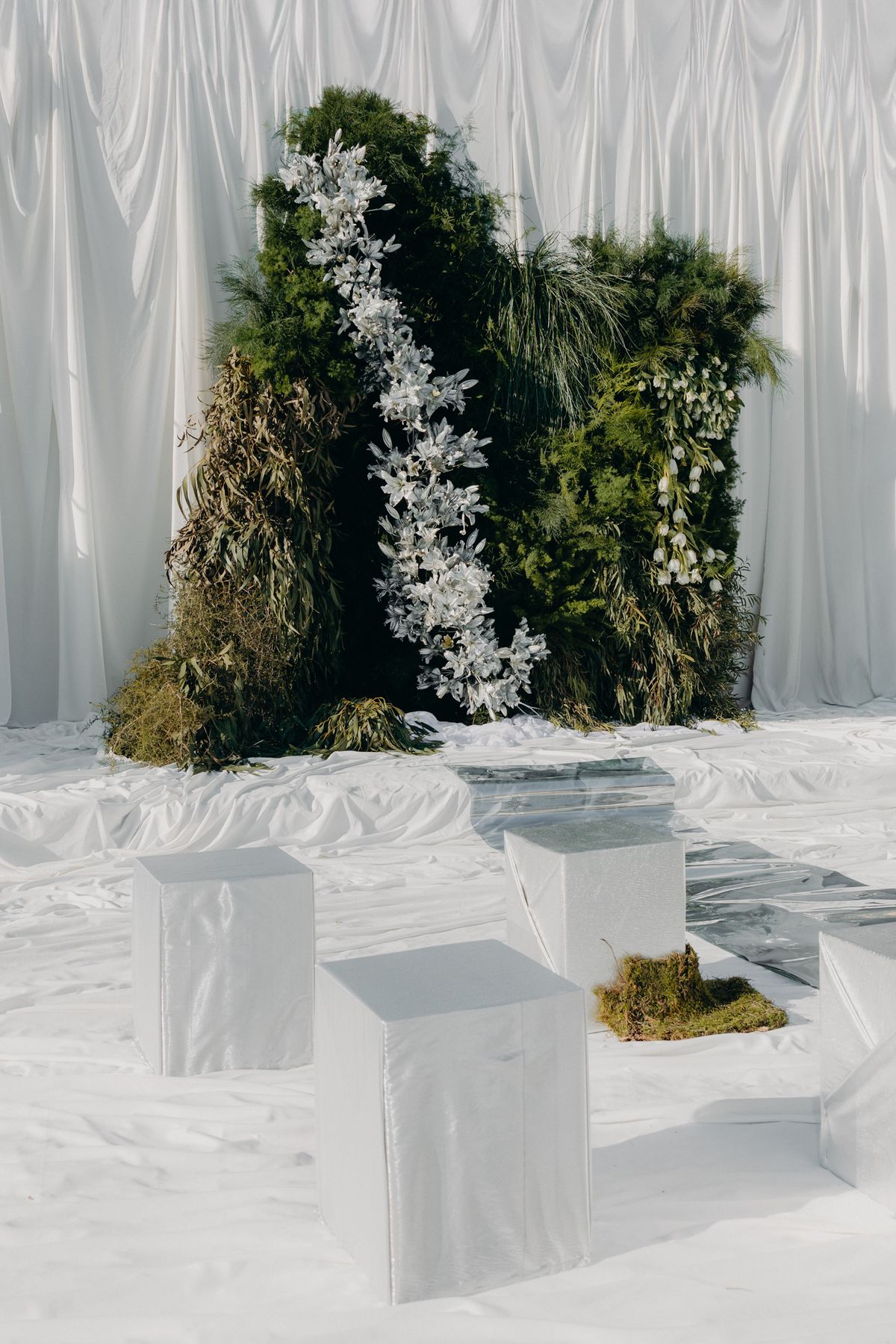 Floral and foliage altar installation against white drapery