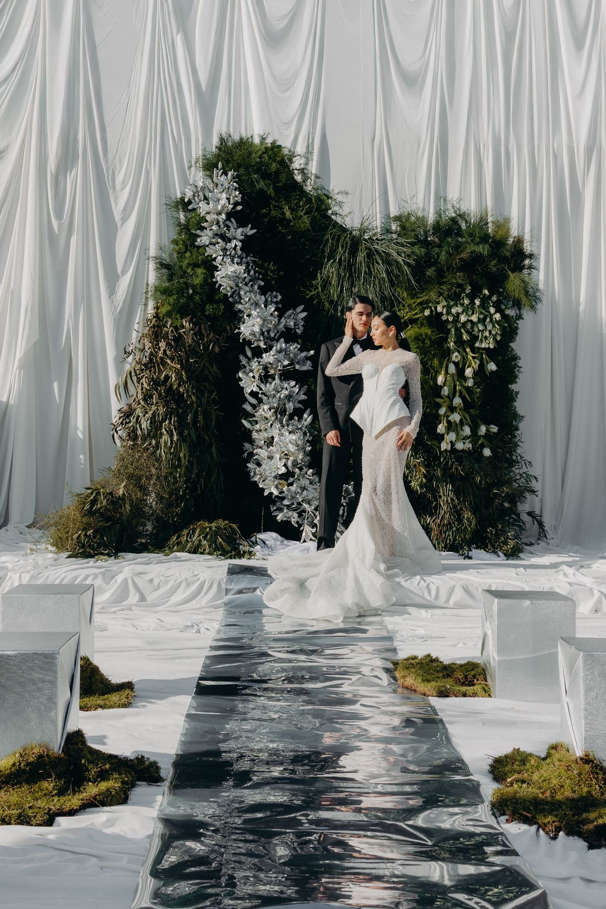 Bride on the mirrored ceremony runway before the floral altar