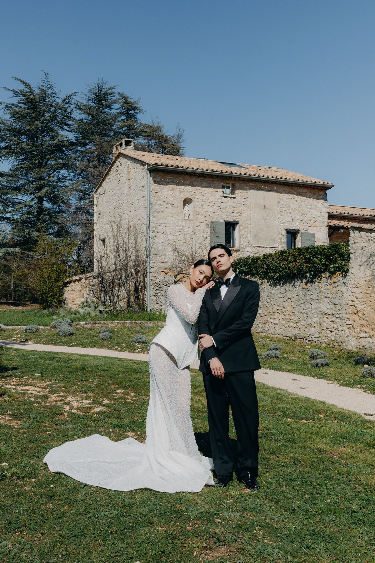 Bride and groom embracing beside the stone Mas
