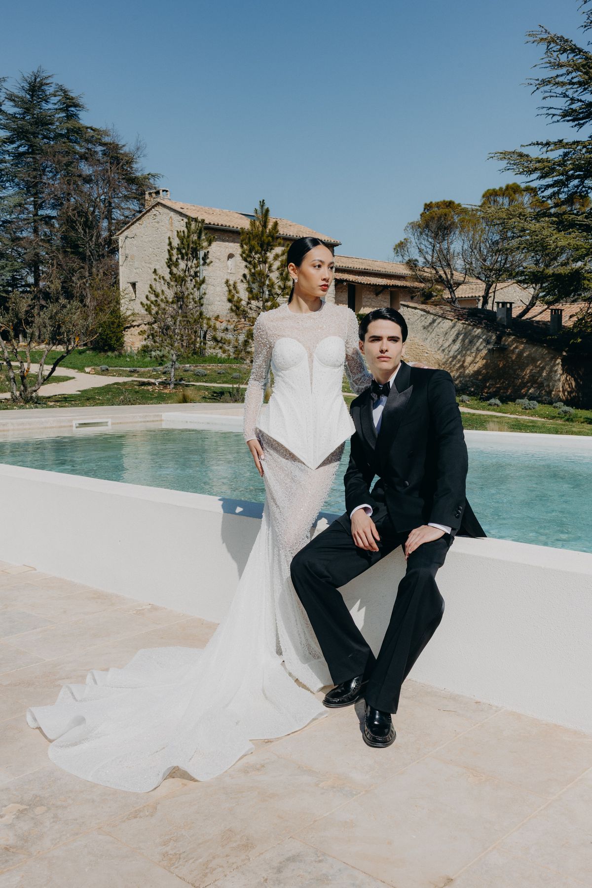 Bride and groom seated at the pool's edge