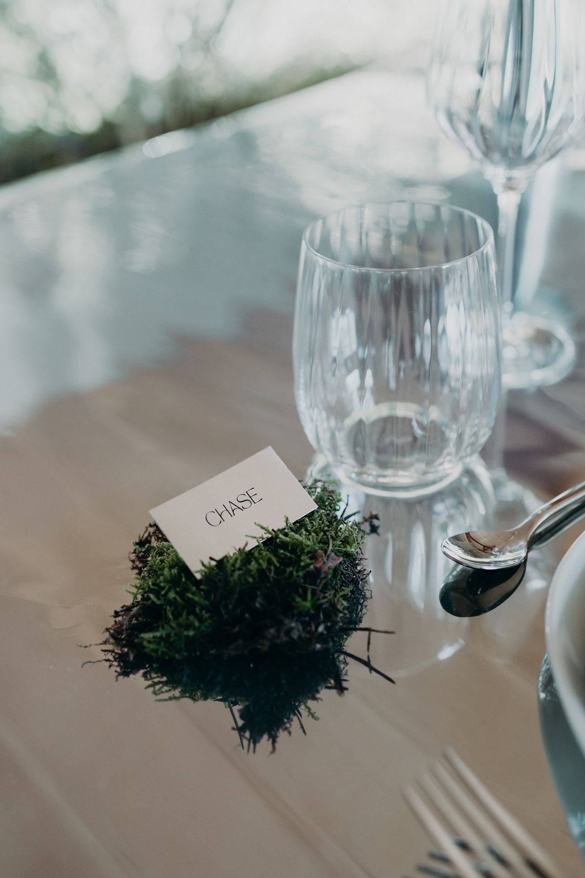 Place card resting on moss beside cut glassware