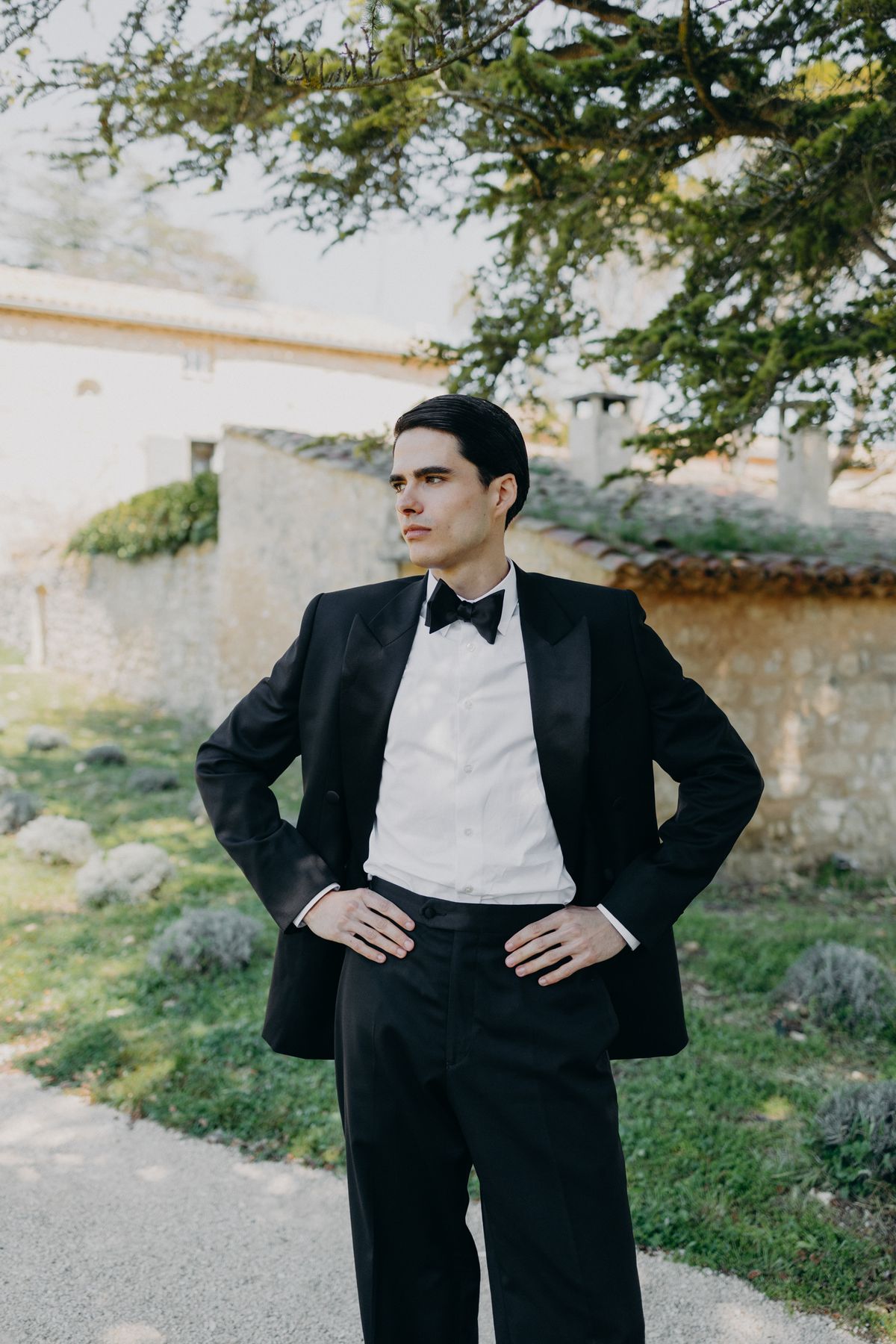 Groom in a black tuxedo beside the stone wall