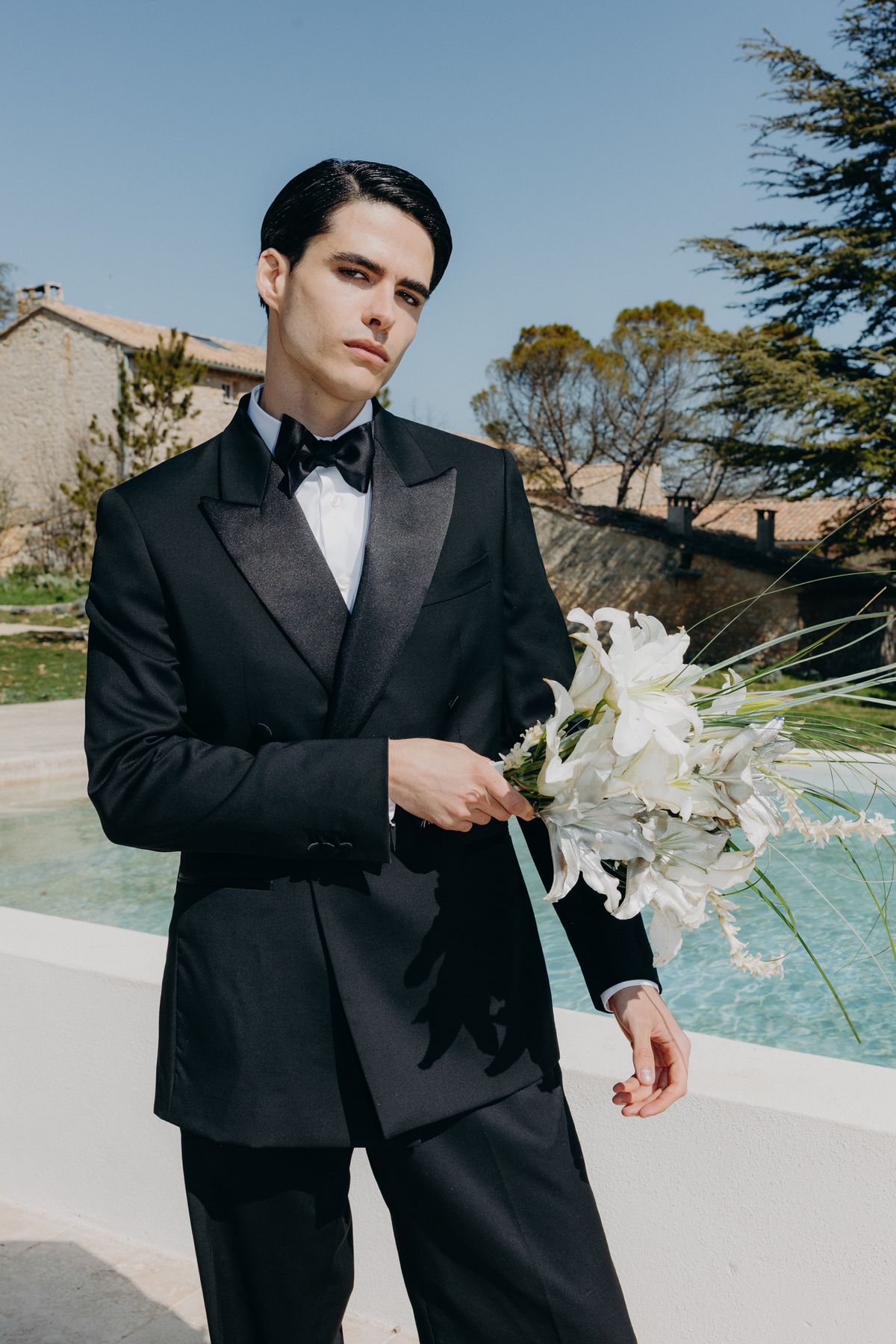Groom in a black tuxedo holding the bouquet