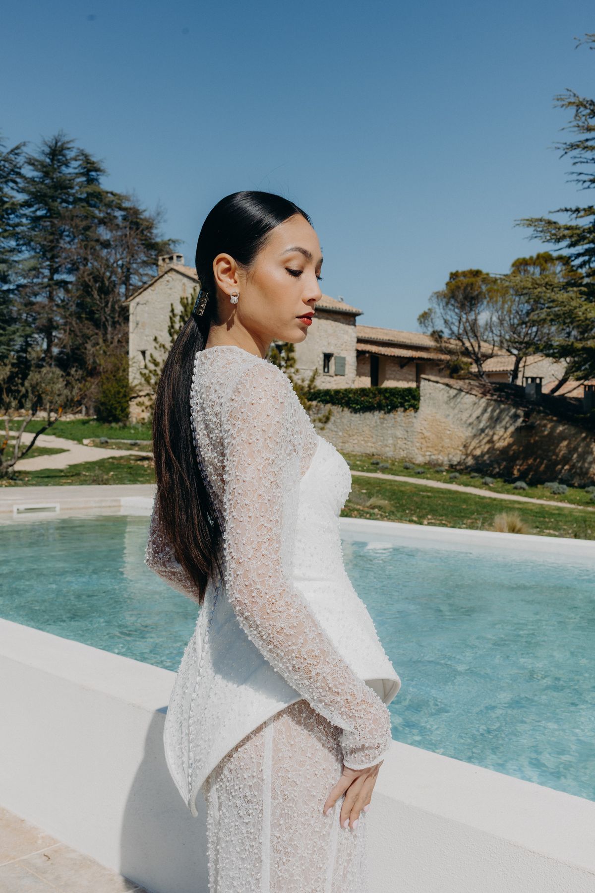 Bride in a beaded gown walking beside the pool