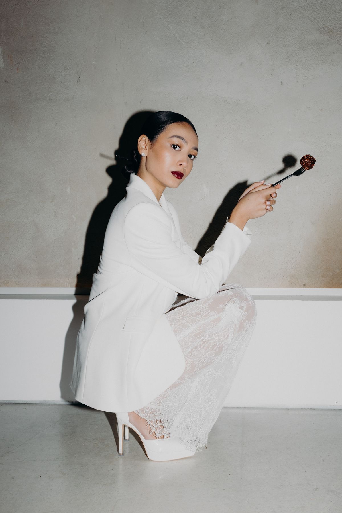 Bride in a white suit holding makeup brushes