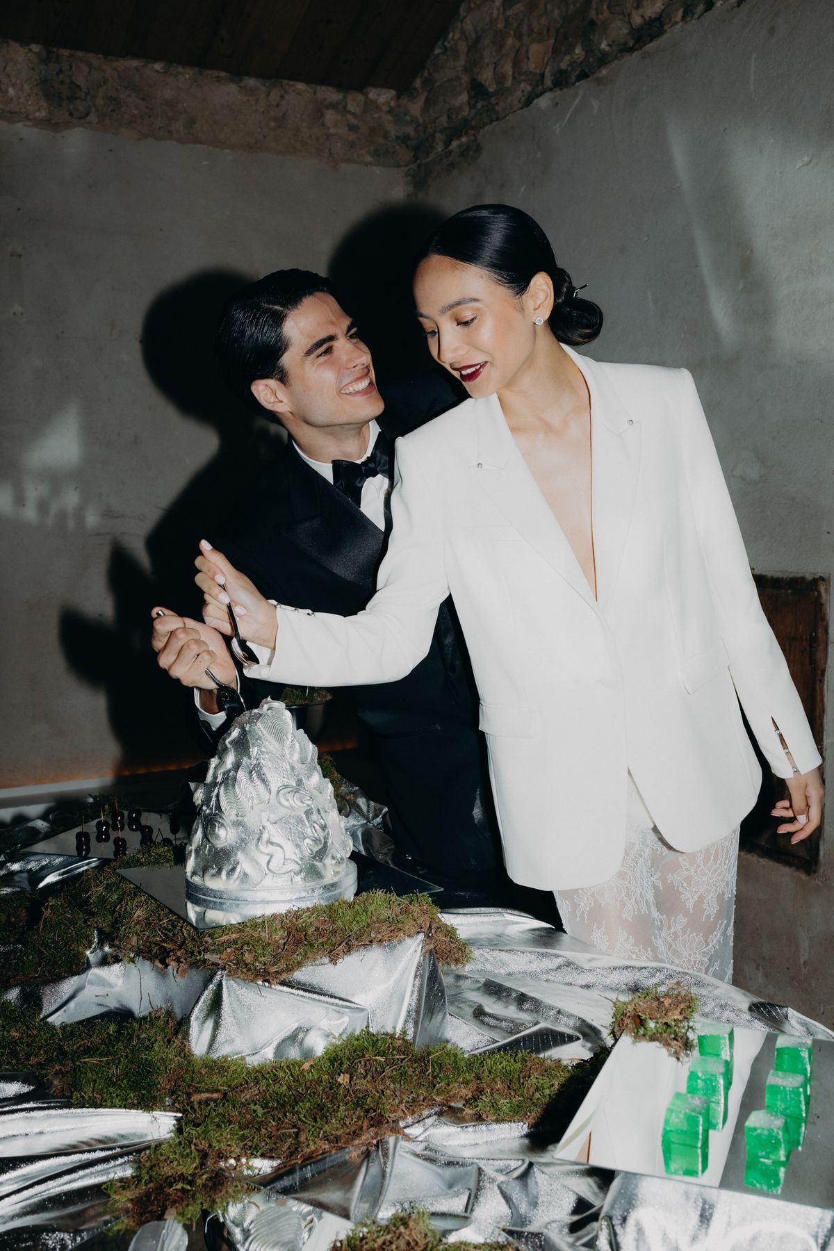 Bride and groom beside the sculptural silver cake