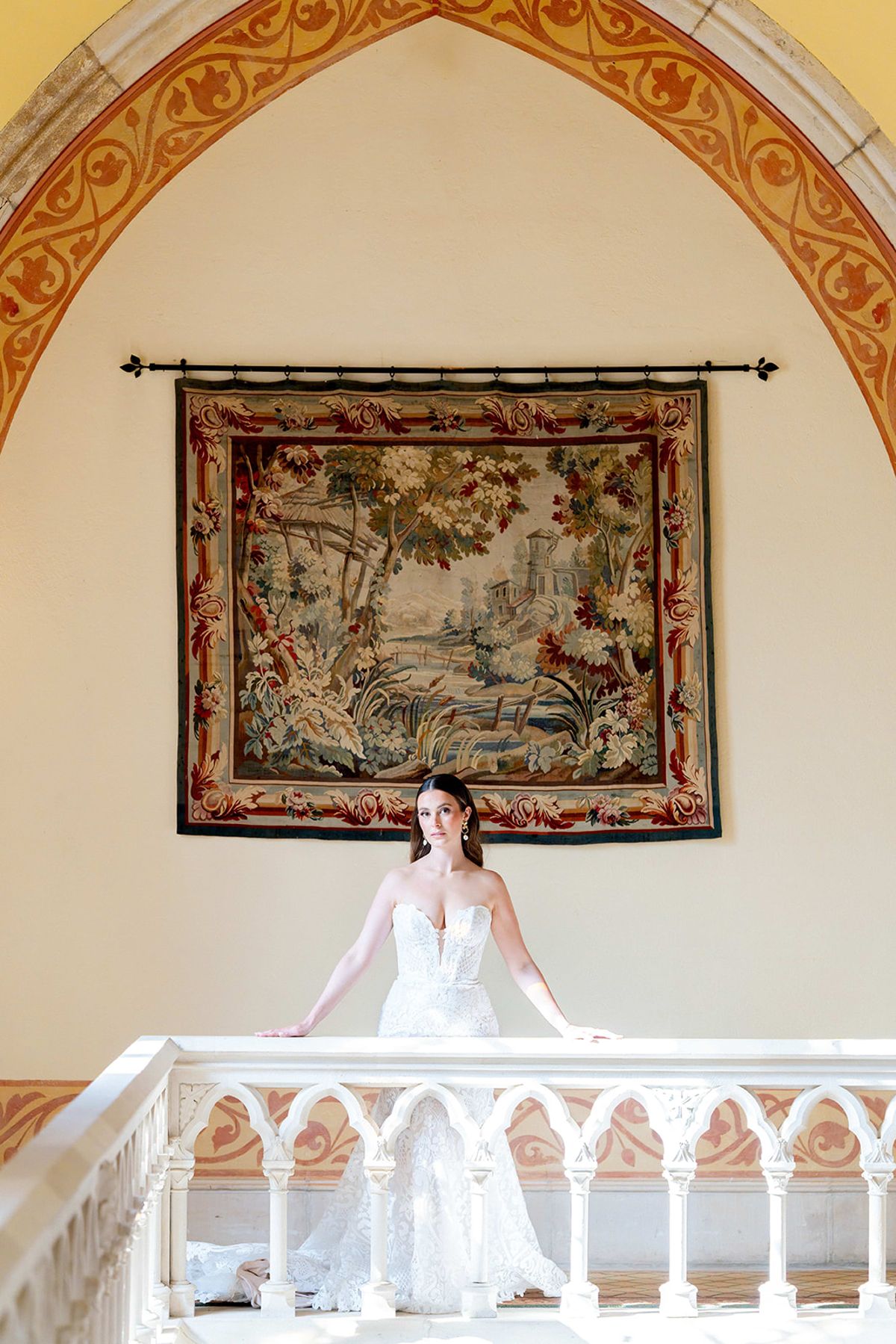 The bride on the abbey balcony in front of a woven tapestry