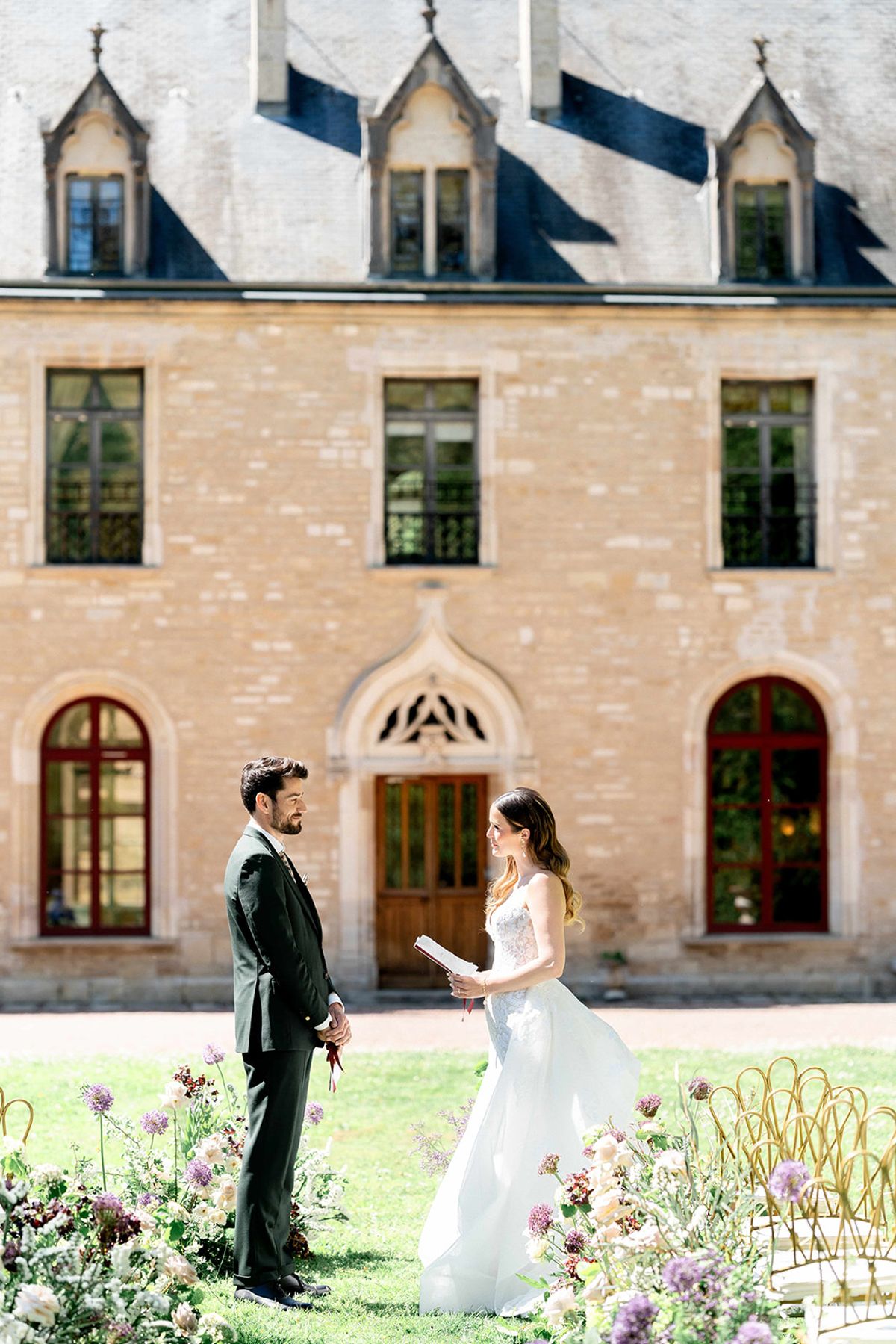 The bride reading from a page to the groom during the ceremony on the lawn