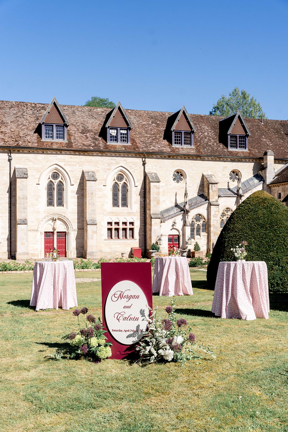 The welcome sign and draped cocktail tables on the lawn in front of the abbey