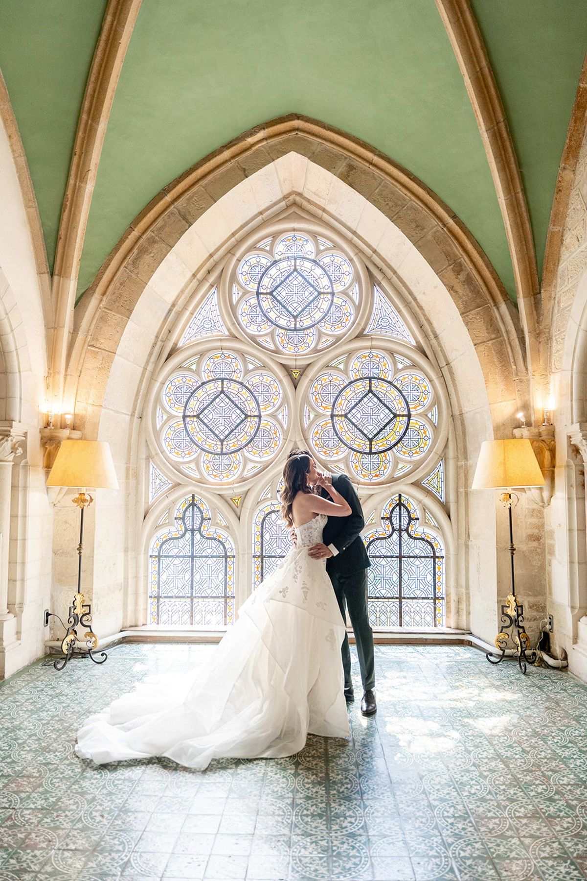 The couple embracing in the abbey chapel beneath the stained glass windows