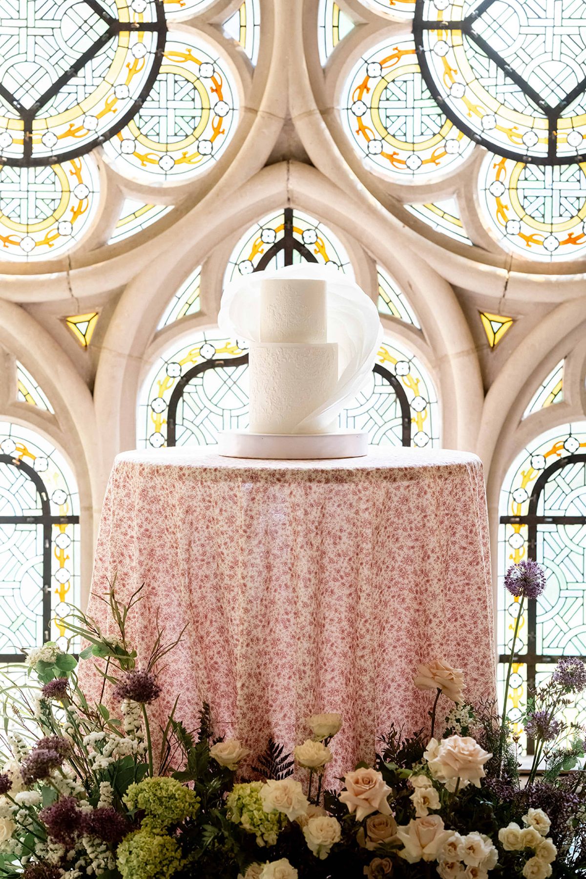 The wedding cake framed by florals in the abbey chapel