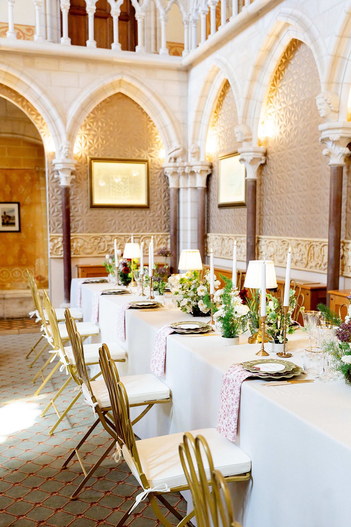 Dinner tables with gold chairs and floral runners in the reception hall