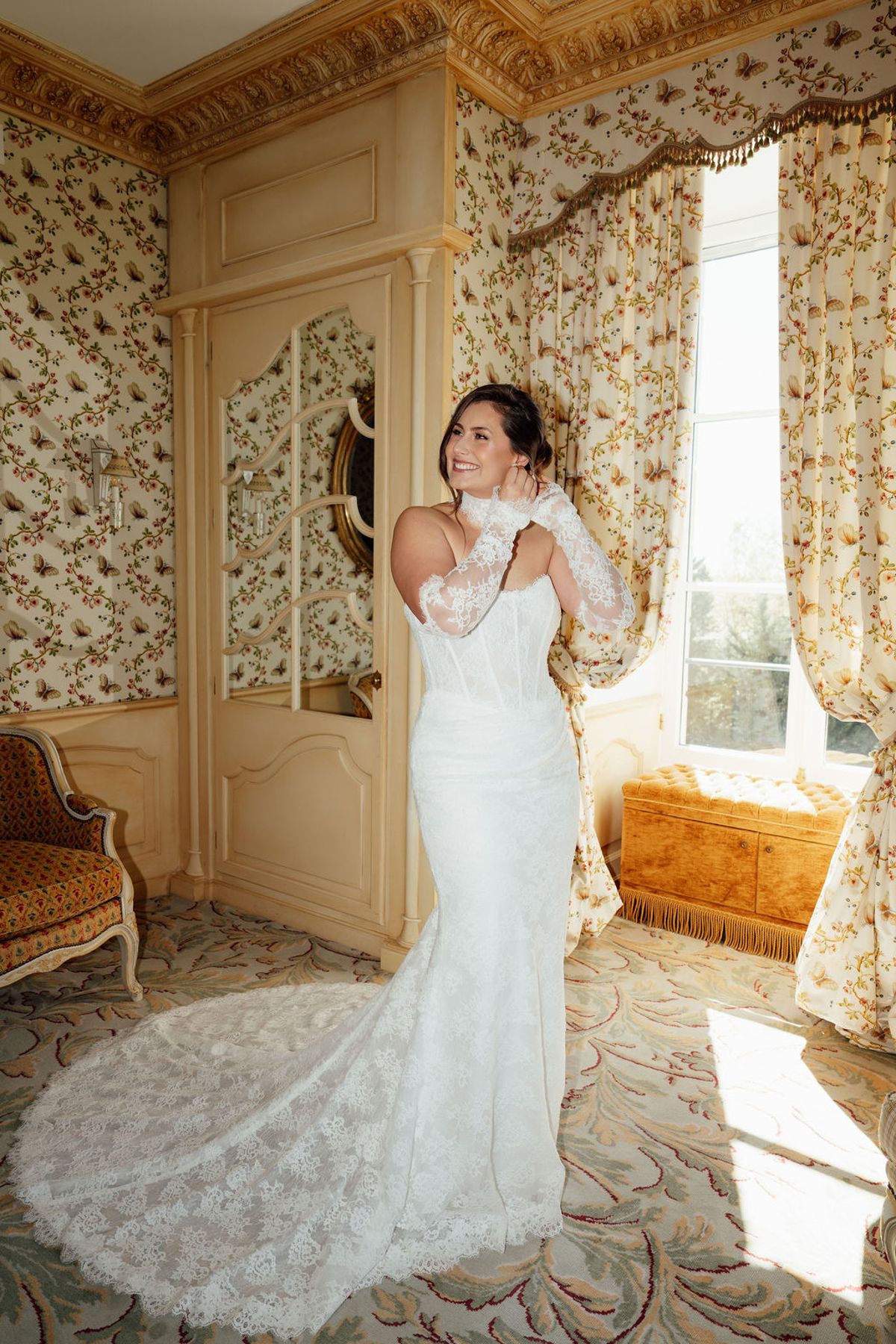 Styled shoot models Harper and Liam: the bride standing full-length by a chateau window, Chateau de Mirambeau, spring editorial