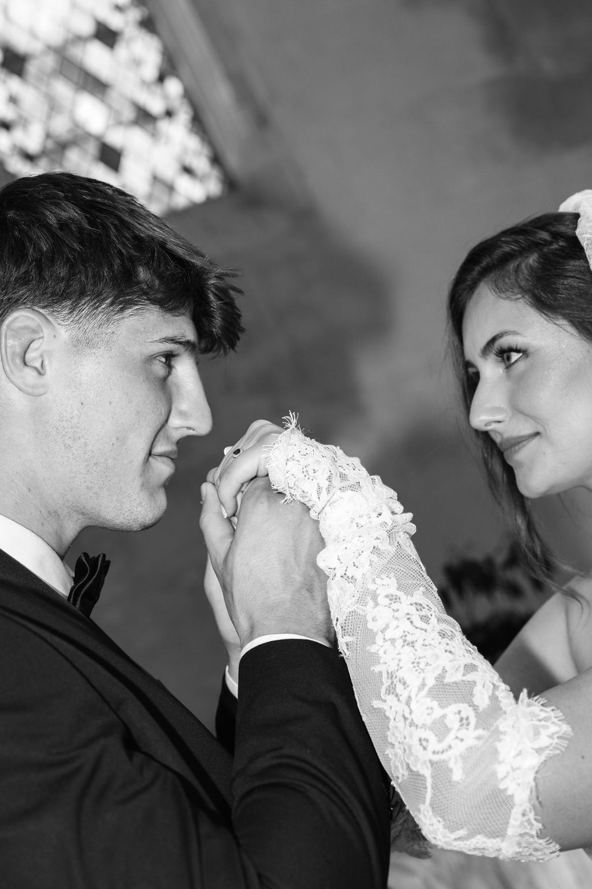 Styled shoot models Harper and Liam: a black-and-white close moment as the groom kisses the bride's hand, Chateau de Mirambeau, spring editorial