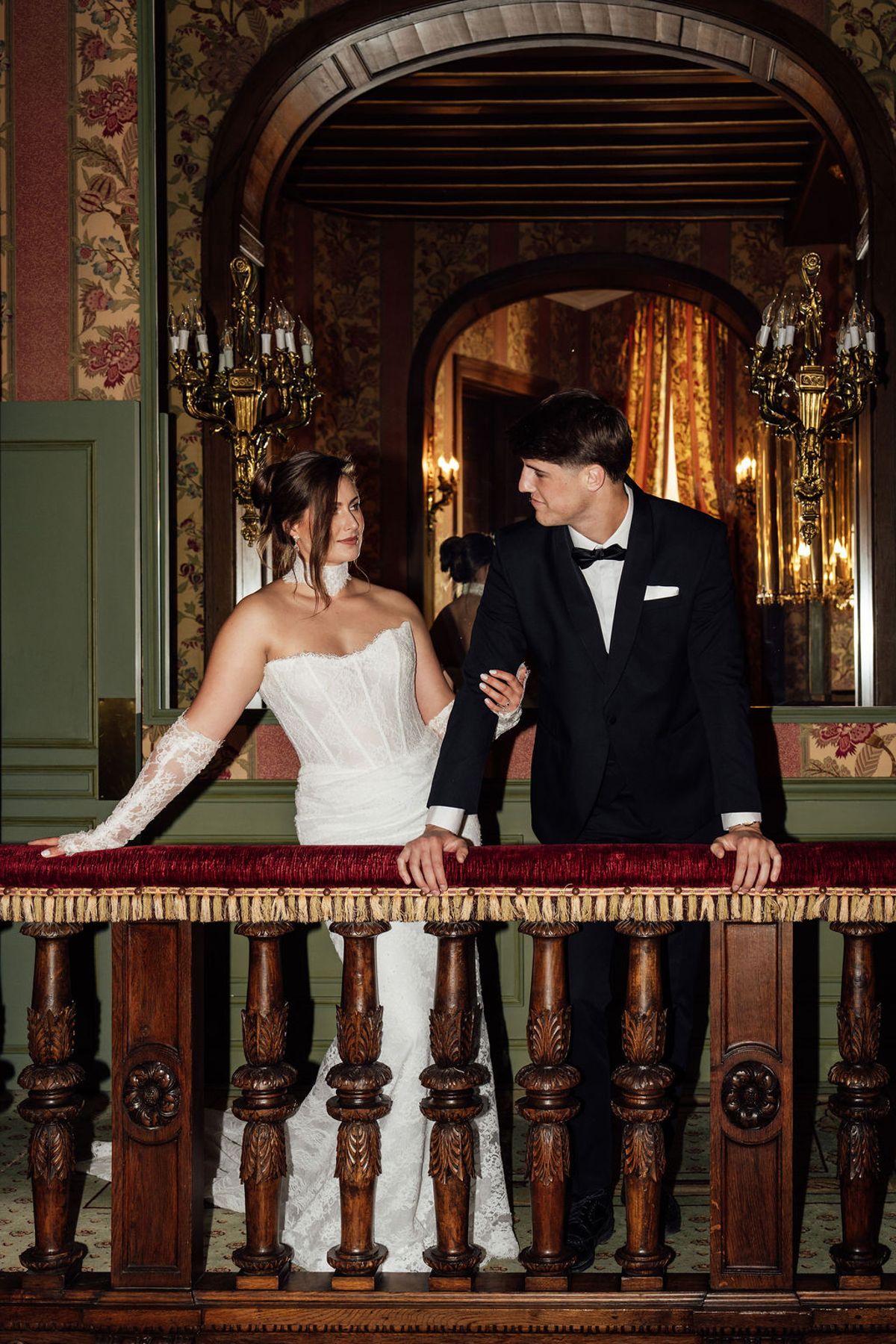 Styled shoot models Harper and Liam: the couple by a carved balcony railing, Chateau de Mirambeau, spring editorial