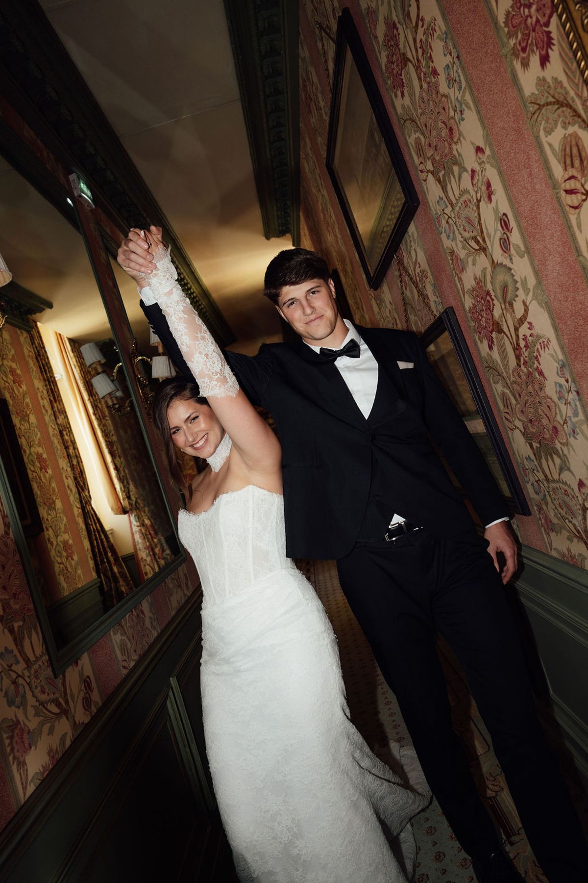Styled shoot models Harper and Liam: the couple with arms raised in a chateau hallway, Chateau de Mirambeau, spring editorial