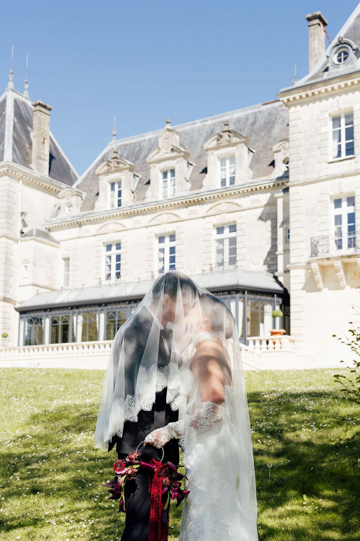 Styled shoot models Harper and Liam: a veiled kiss with the chateau facade behind, Chateau de Mirambeau, spring editorial