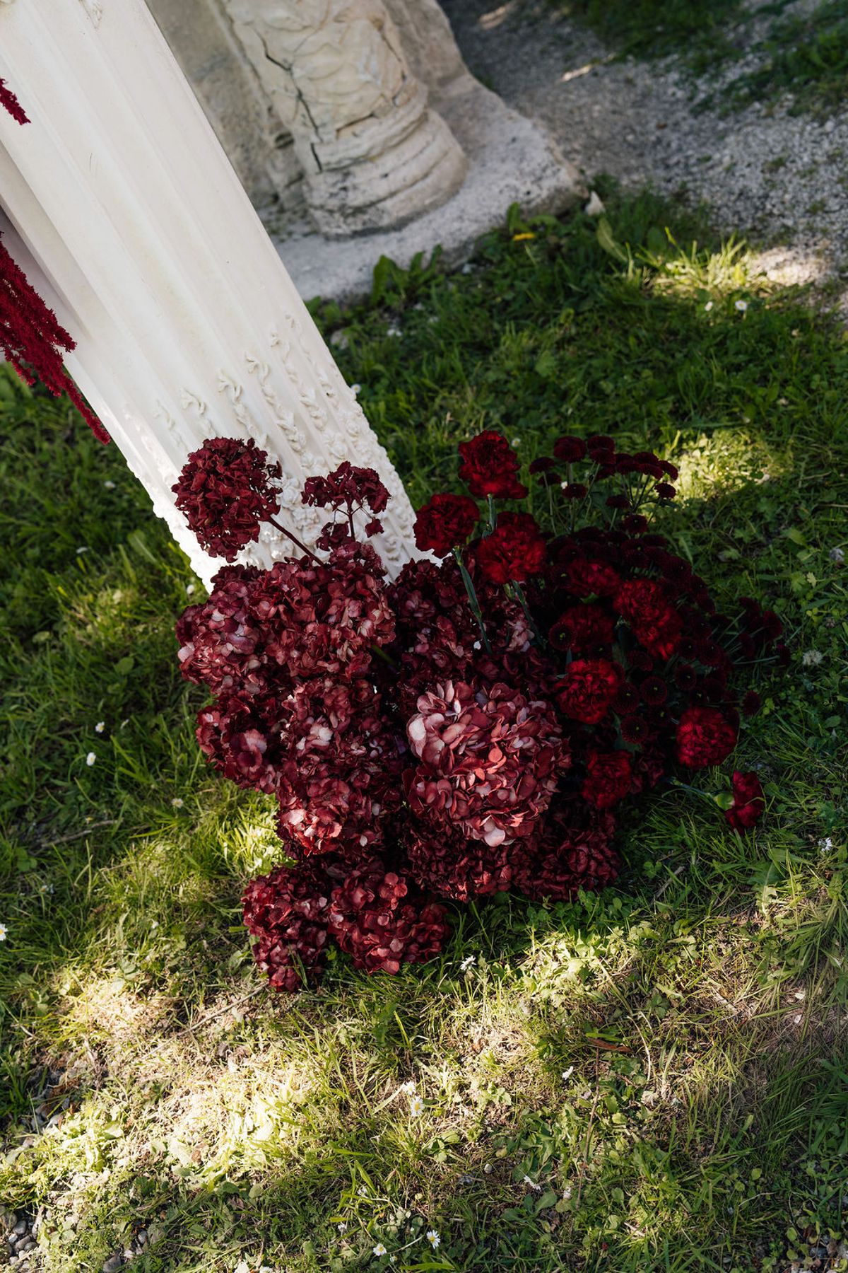 Styled shoot models Harper and Liam: deep-red dahlias and orchids massed against the stone, Chateau de Mirambeau, spring editorial