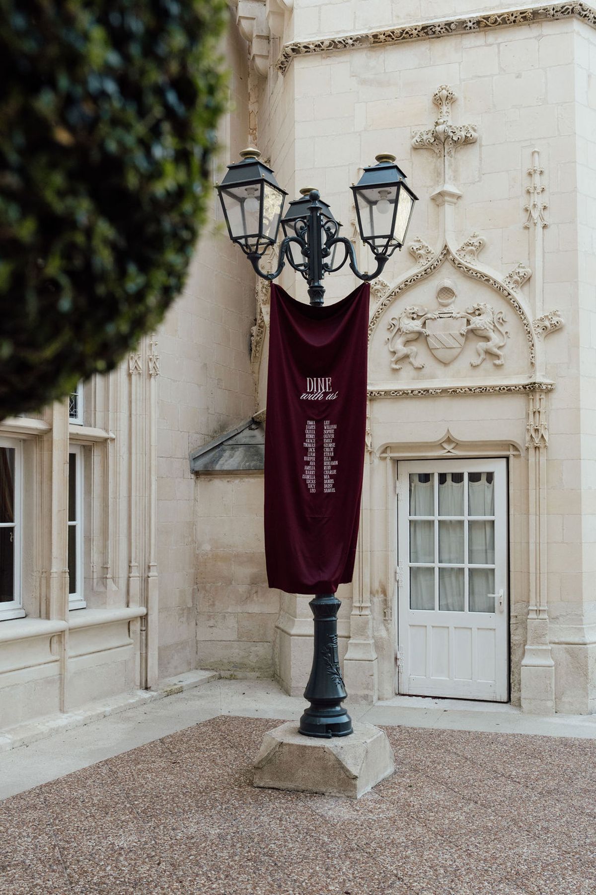 Styled shoot models Harper and Liam: a burgundy banner hung from a lamppost in the courtyard, Chateau de Mirambeau, spring editorial