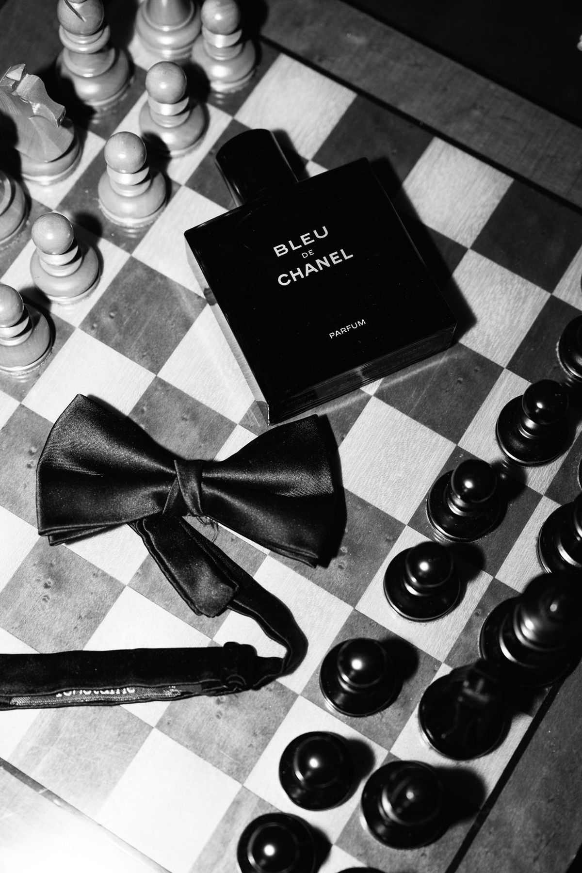 Styled shoot models Harper and Liam: black-and-white detail of a bow tie and chess pieces beside a Chanel bottle, Chateau de Mirambeau, spring editorial