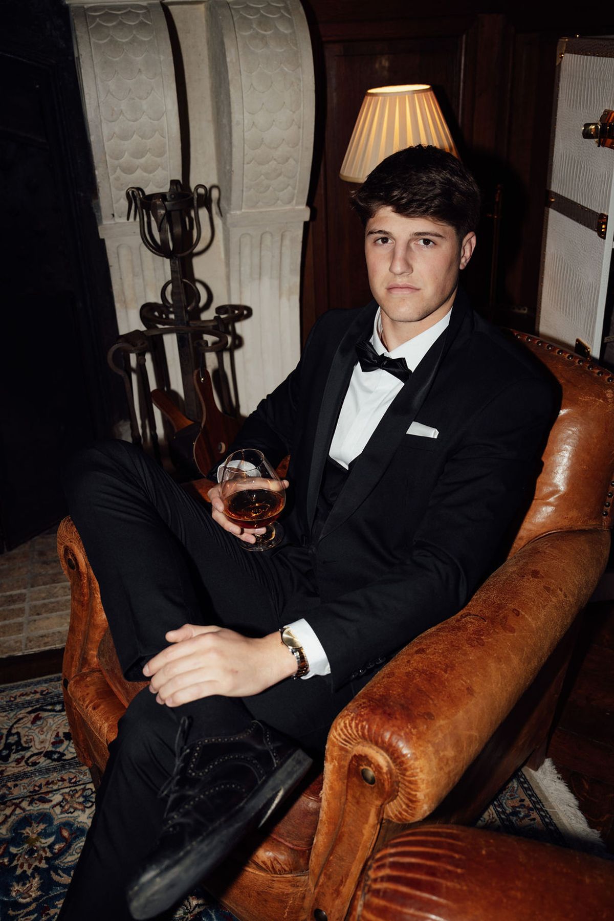 Styled shoot models Harper and Liam: black-and-white portrait of the groom seated with a drink in hand, Chateau de Mirambeau, spring editorial
