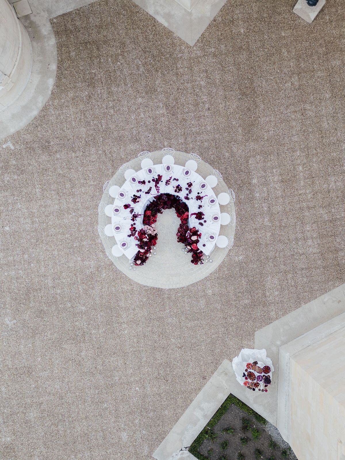 Styled shoot models Harper and Liam: drone view of the round reception table and its burgundy floral horseshoe centrepiece, Chateau de Mirambeau, spring editorial
