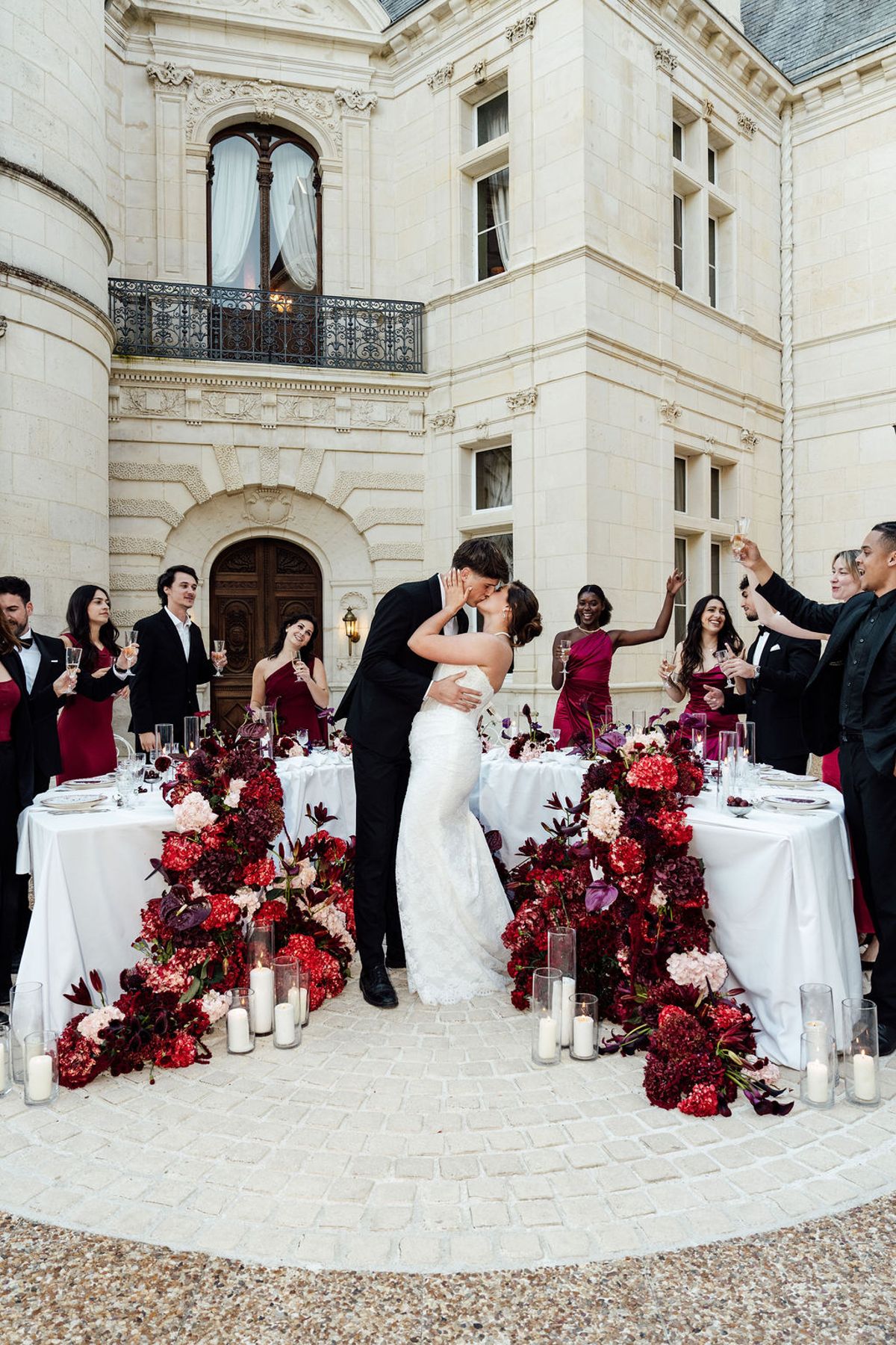 Styled shoot models Harper and Liam: guests toasting as the couple kiss at the table, Chateau de Mirambeau, spring editorial