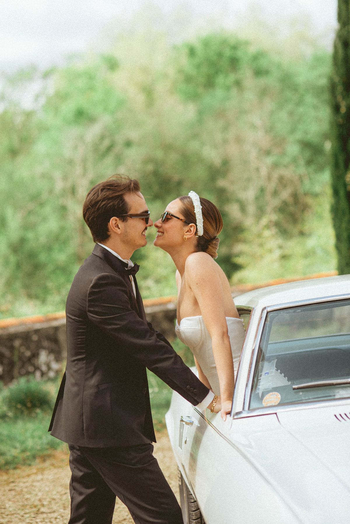 Couple kissing by vintage car at Chateau de Campet