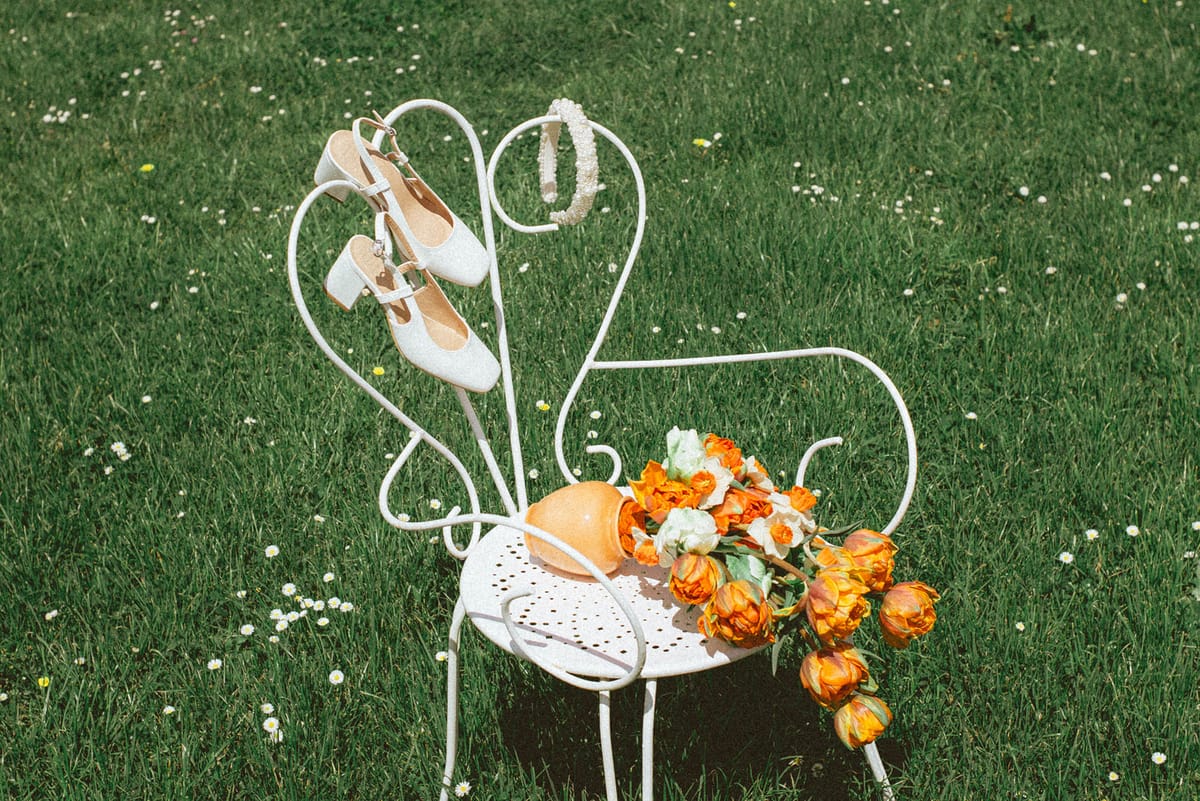 Bridal shoes and orange bouquet on garden chair at Chateau de Campet