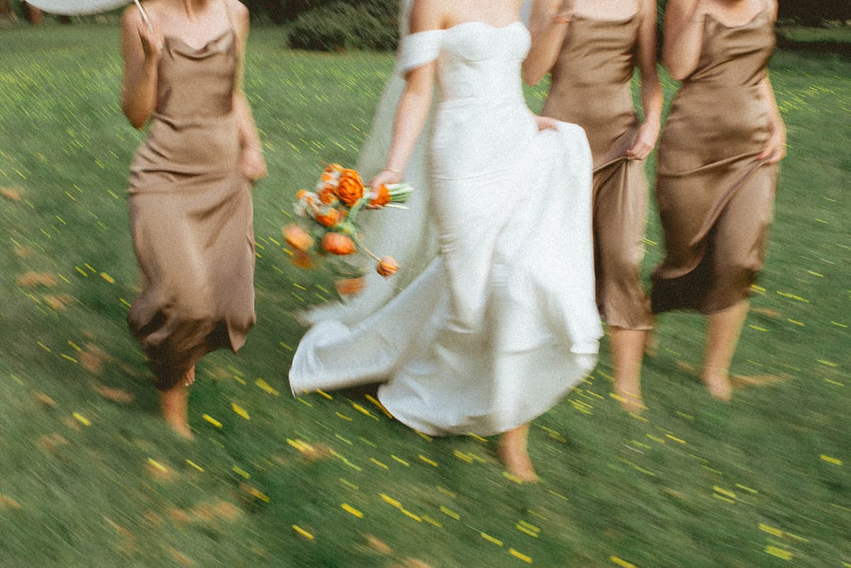 Bride and bridesmaids running on lawn at Chateau de Campet