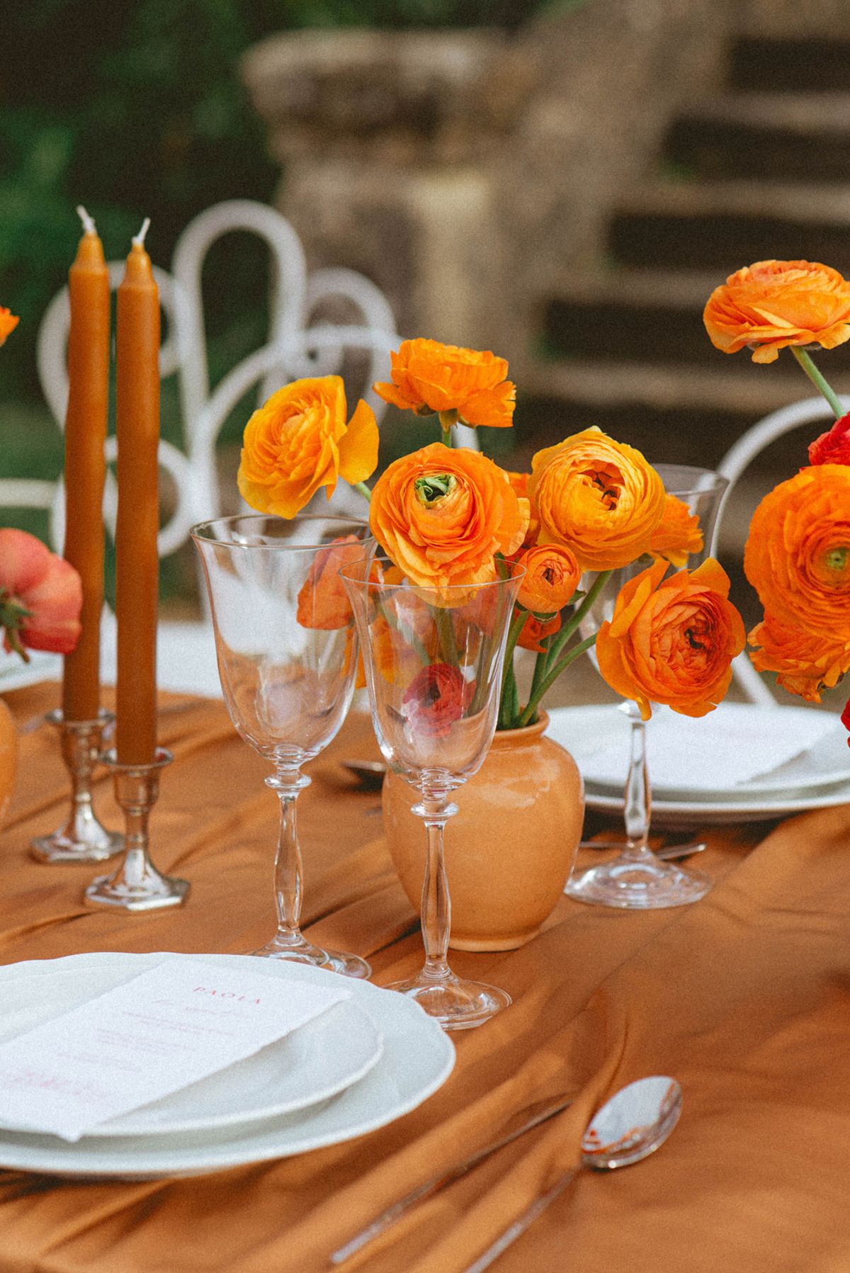 Orange ranunculus centrepiece on amber linen at Chateau de Campet