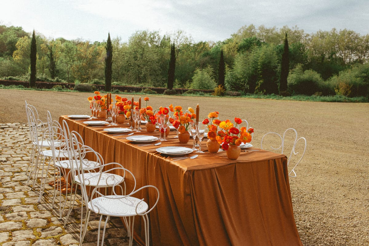 Reception table with orange flowers and cypress trees at Chateau de Campet