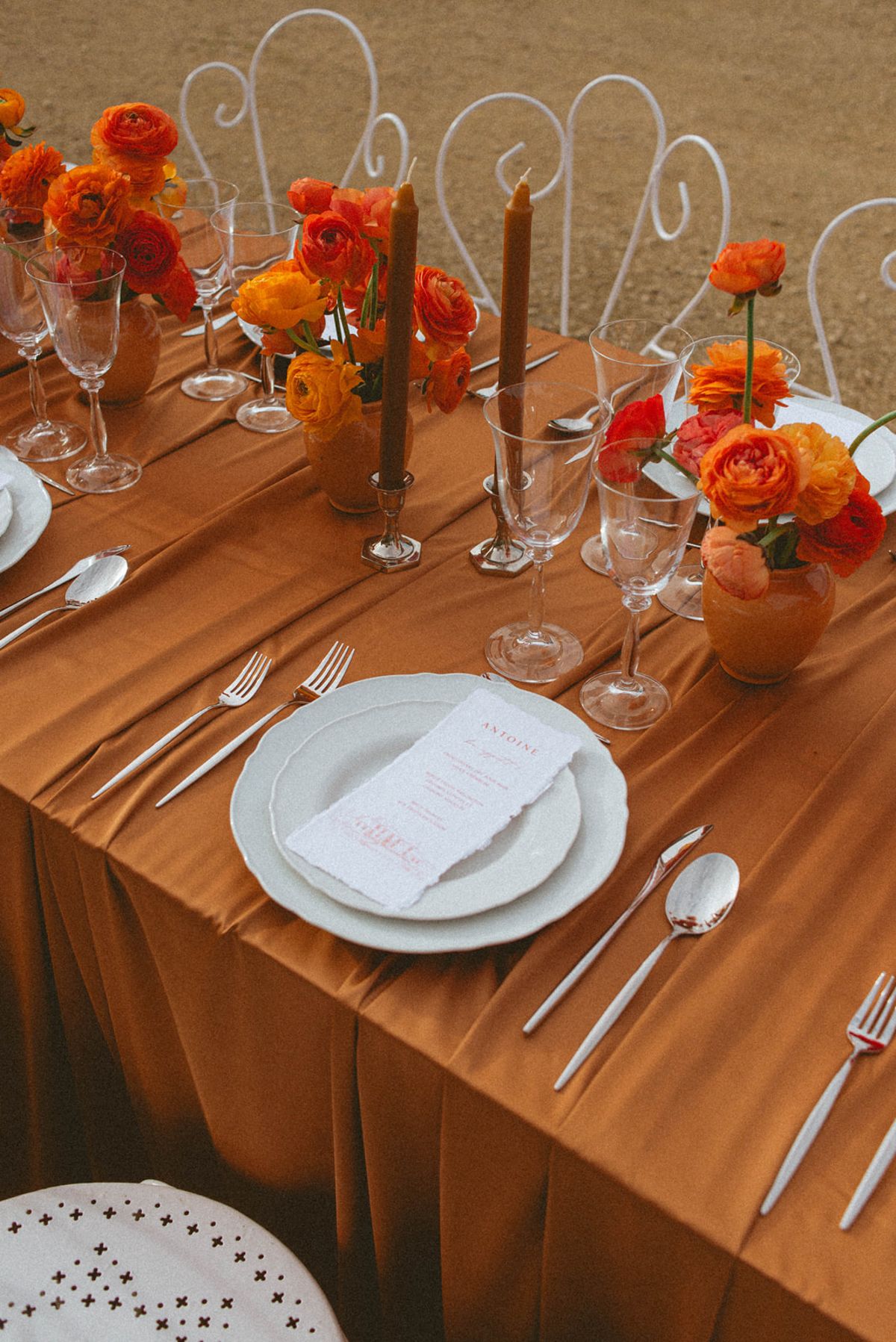 Place setting with orange flowers on amber cloth at Chateau de Campet
