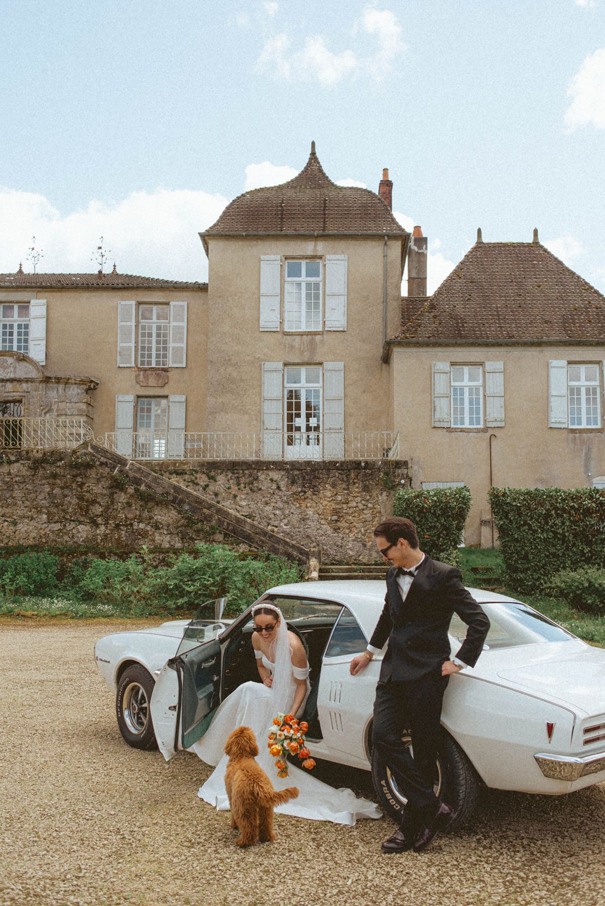 Couple with dog and vintage car at Chateau de Campet