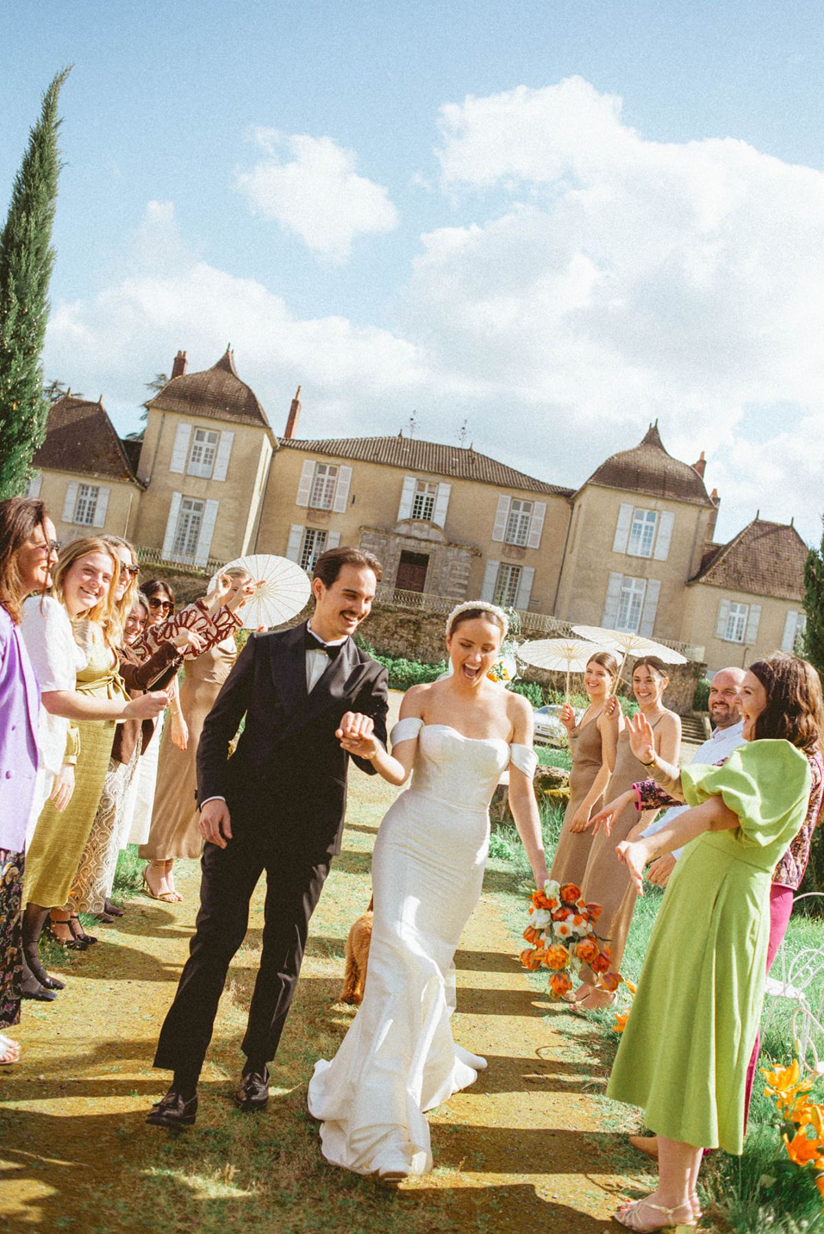 Couple walking aisle with guests cheering at Chateau de Campet