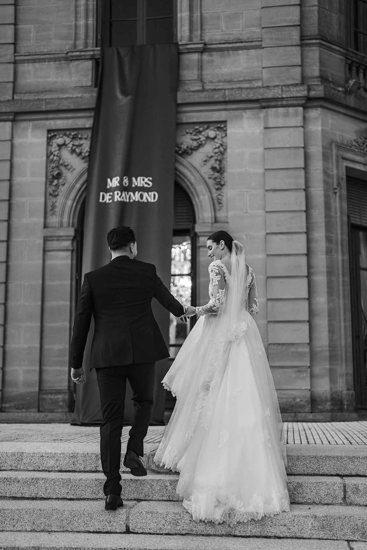 Couple climbing chateau steps hand in hand at Chateau du Terral in black and white