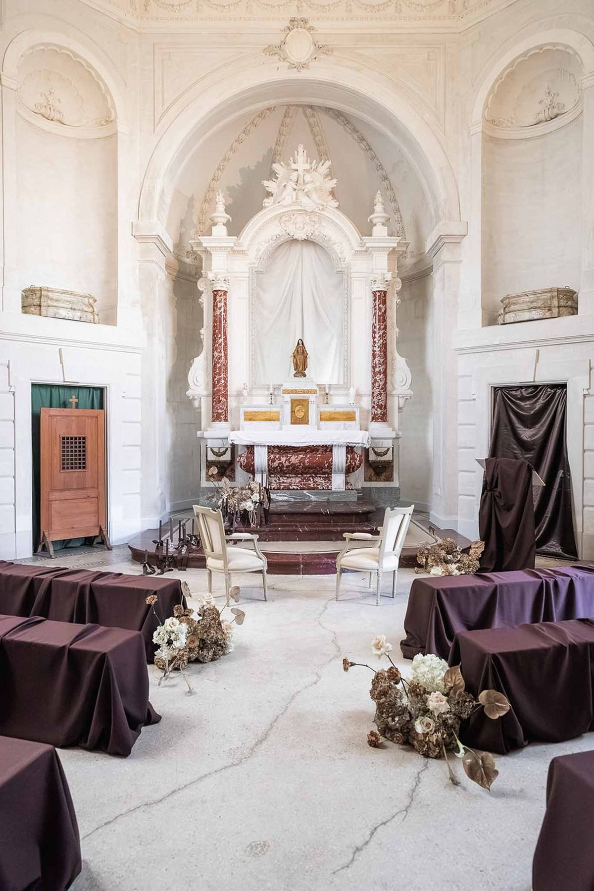 Chapel interior with dark-draped pews and dried florals at Chateau du Terral