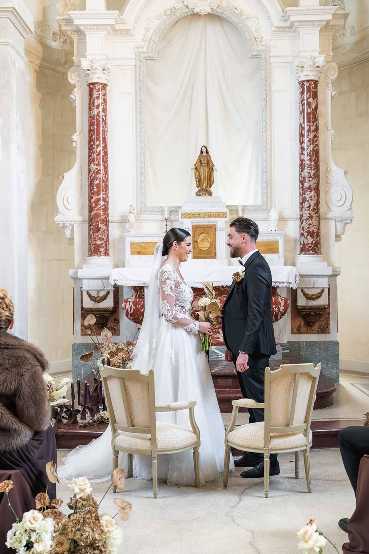 Couple holding hands at baroque chapel altar during ceremony at Chateau du Terral