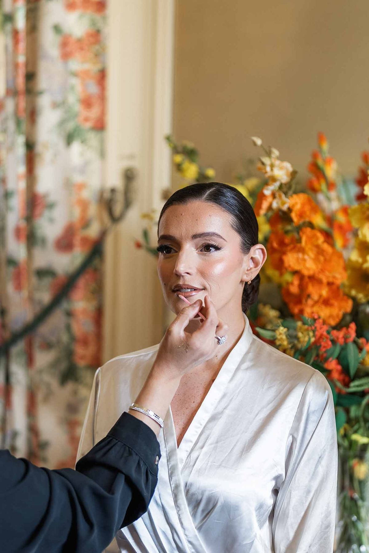 Bride getting makeup applied in silk robe at Chateau du Terral