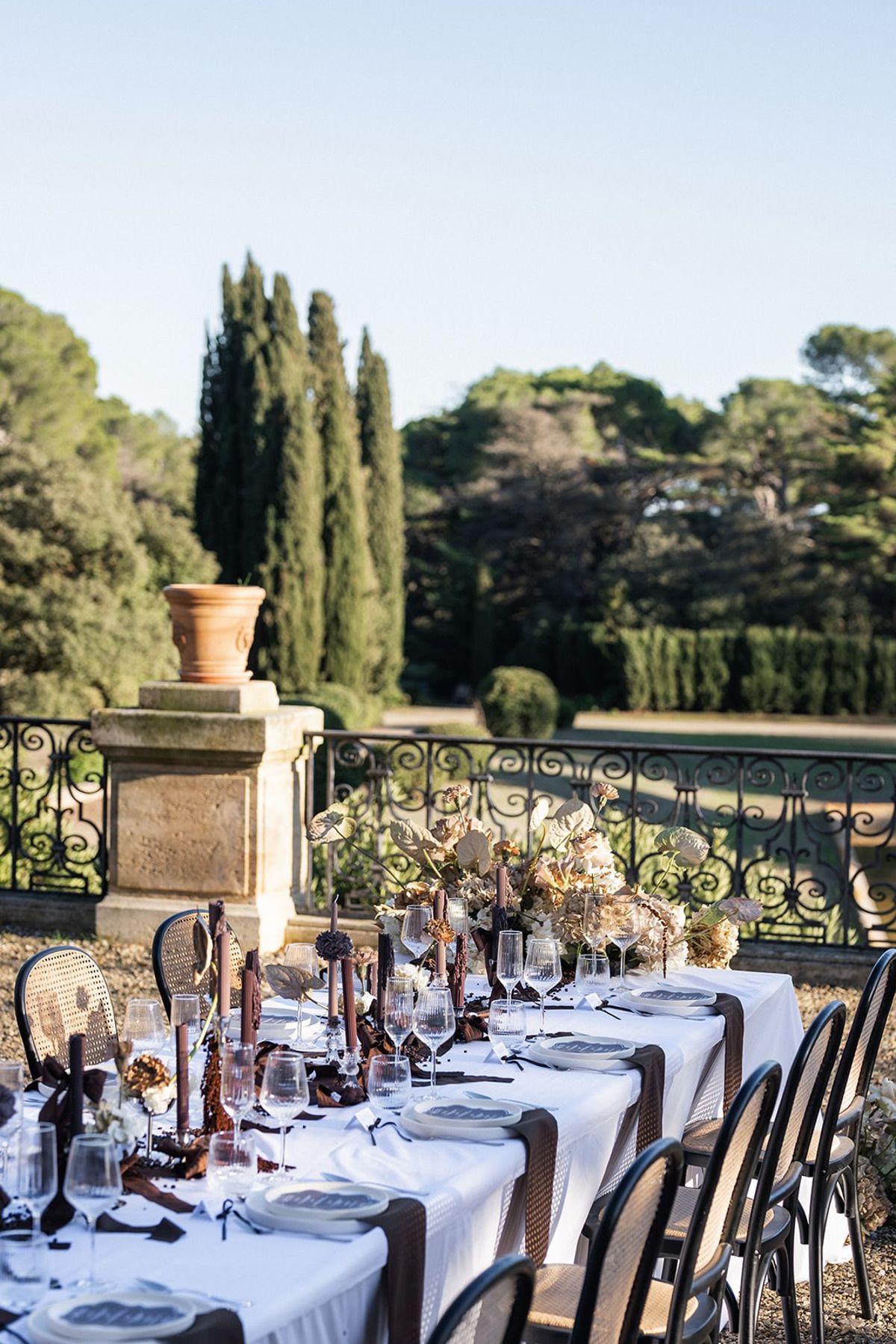 Terrace reception table with dried floral centrepiece beside cypress garden at Chateau du Terral wedding