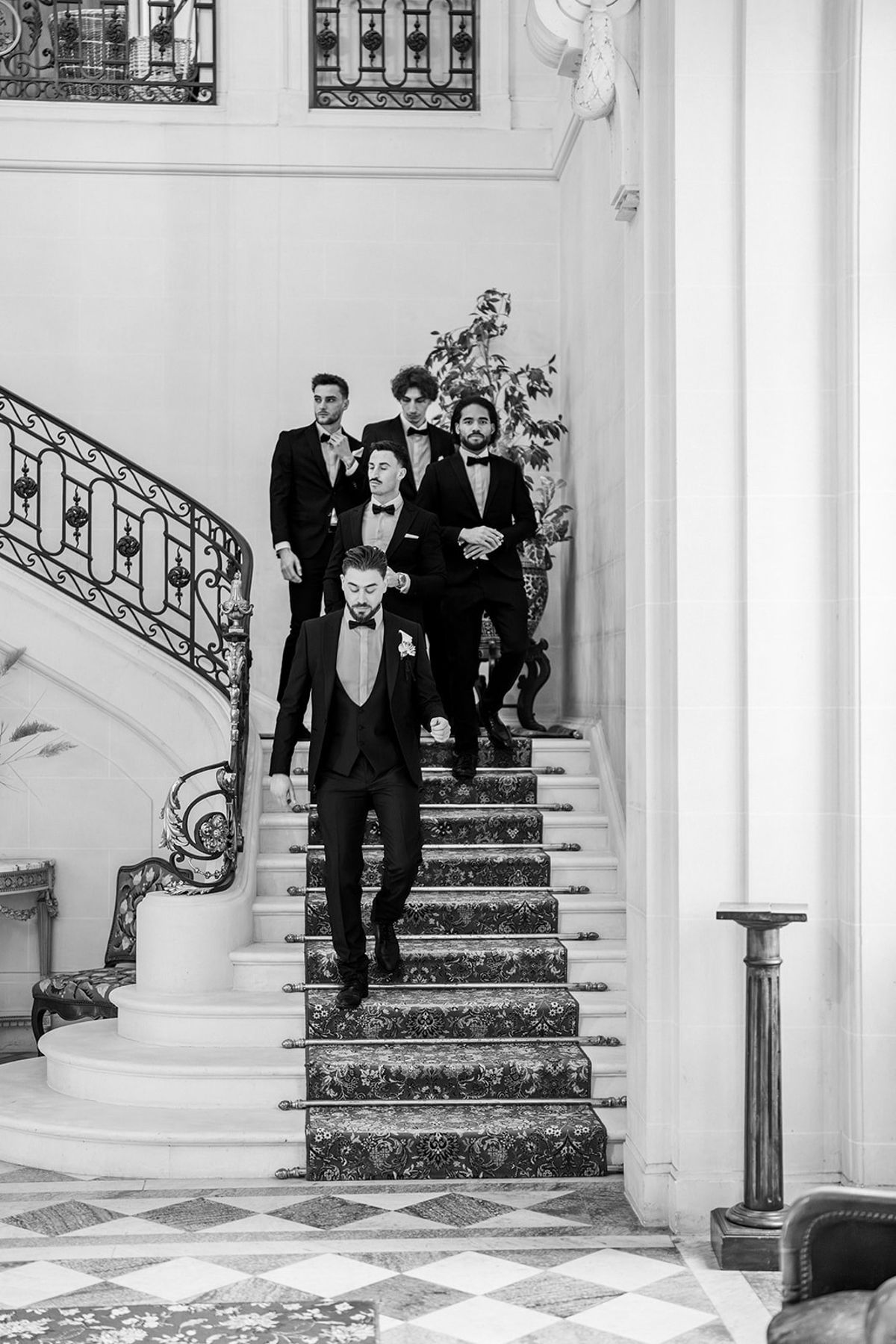 Black and white groom and groomsmen on grand chateau staircase at Chateau du Terral
