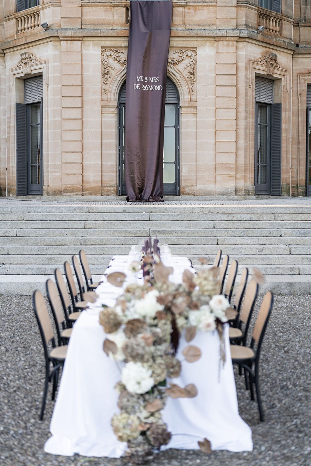 Cascading dried floral runner with brown monogram banner at Chateau du Terral