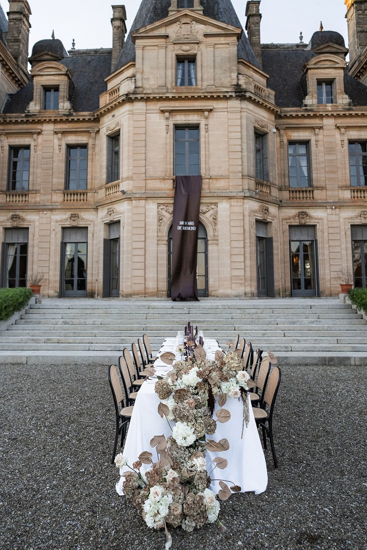 Reception table with cascading florals before chateau facade at Chateau du Terral wedding