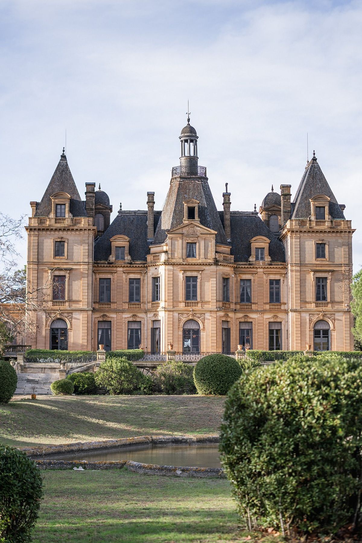 Front facade of Chateau du Terral with mansard turrets and reflecting pond at Chateau du Terral